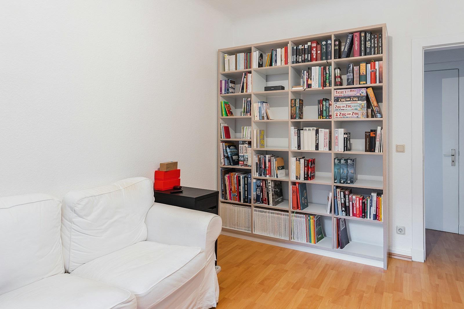 Bela biblioteka u dnevnoj sobi sa sofom